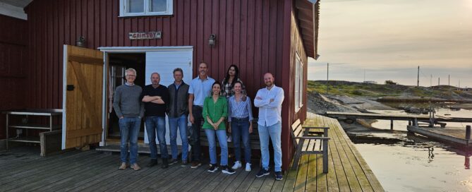 People standing outside a cabin near the ocean